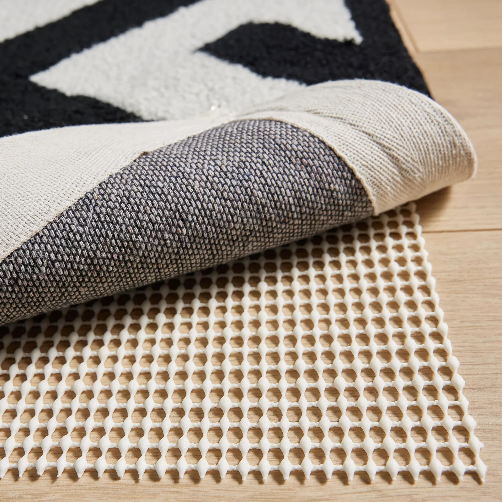 The corner of a rug lifted off its pad: felt above, natural rubber against the floor.